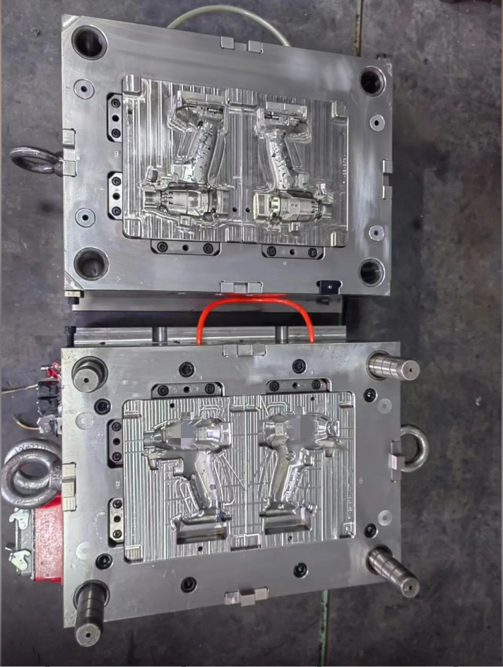 Two-shot injection mold with rotating core and power tool housing cavities