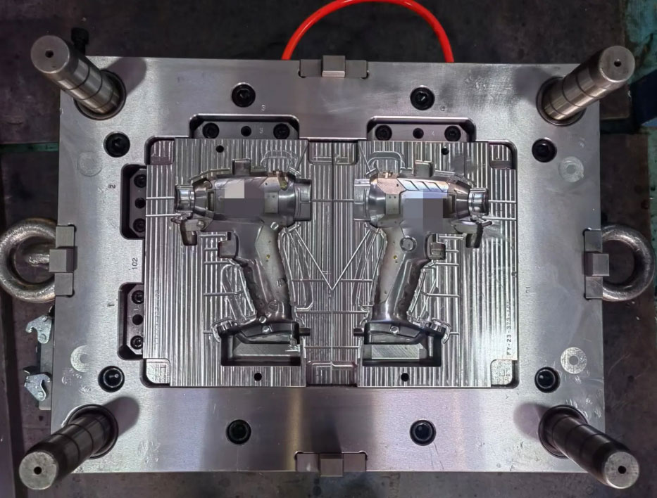 Two-shot injection mold with rotating core and power tool housing cavities